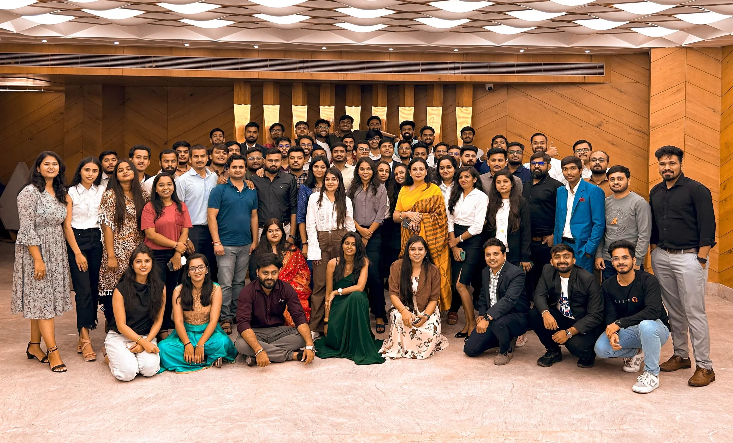 A large group of people pose for a group photo in a room with wood-paneled walls.