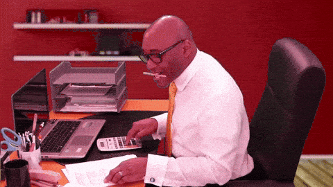 Businessman calculating numbers with calculator, papers, and laptop while working in office at desk