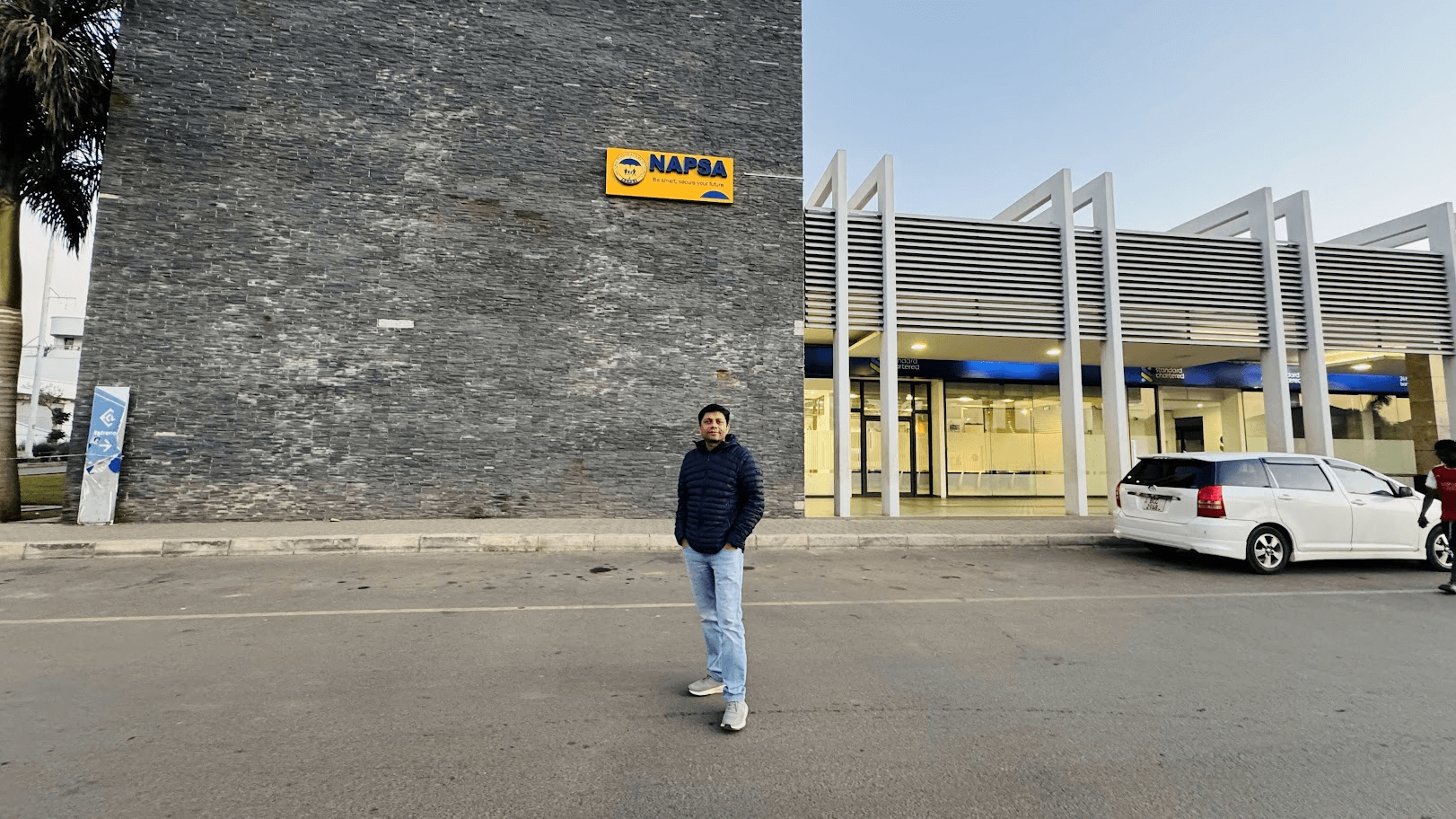 Modern NAPSA office building exterior with customer service centre signage and a visitor standing near the entrance
